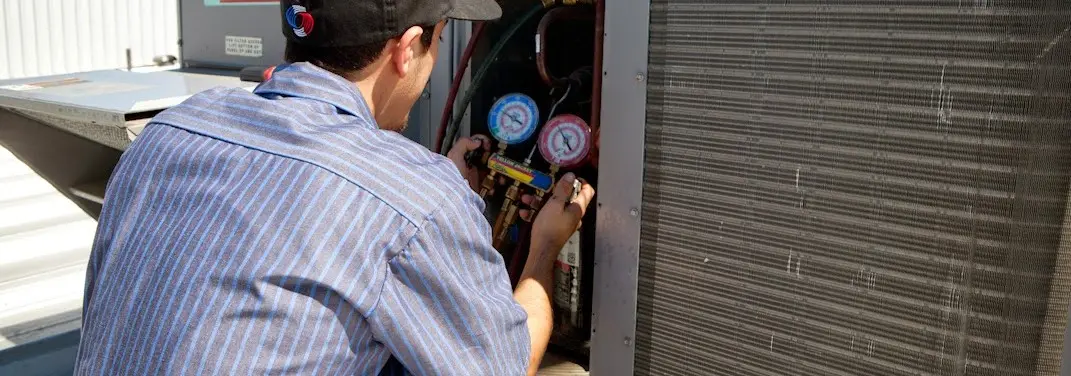HVAC technician servicing a condenser unit in Apache Junction